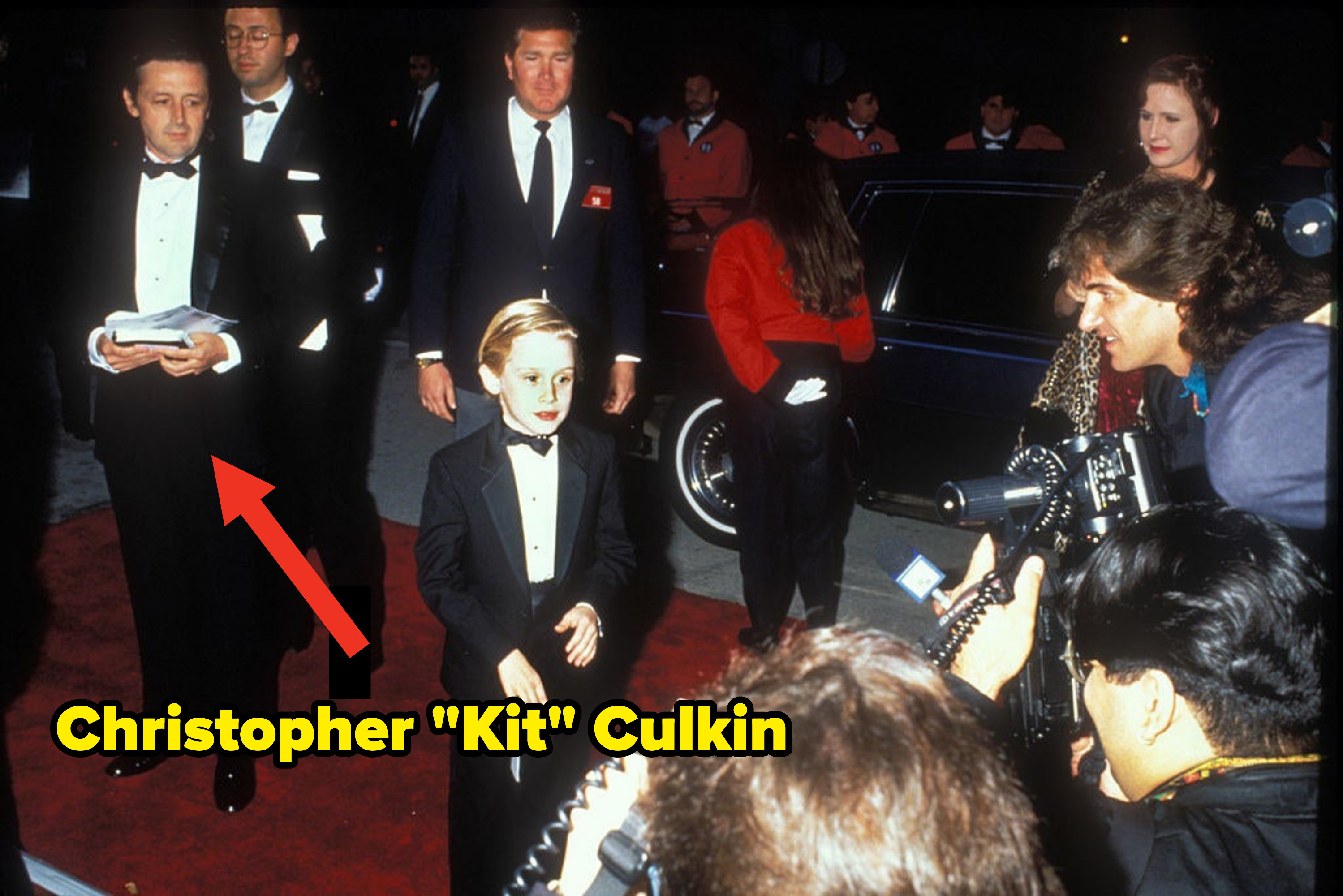 A younf Macaulay walking the red carpet with his dad Kit behind him