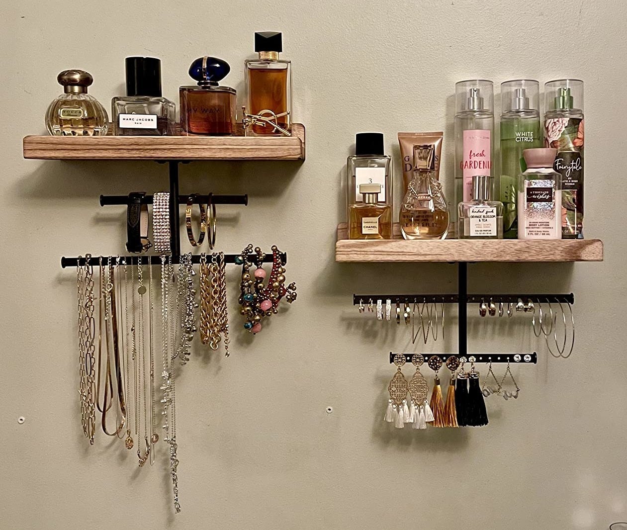 a reviewer photo of the wood and metal organizers hanging on a wall, filled with jewelry and perfumes
