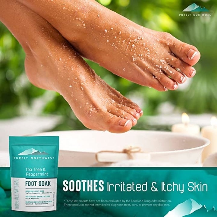 Feet hanging above foot bath with salt flakes and water on them; tea tree and peppermint foot soak bag  shown beneath