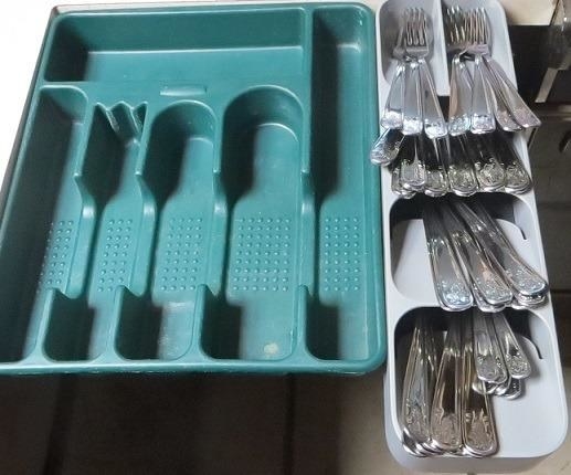 a reviewer photo of a large empty standard silverware organizer next to the space-saving one, filled with cutlery