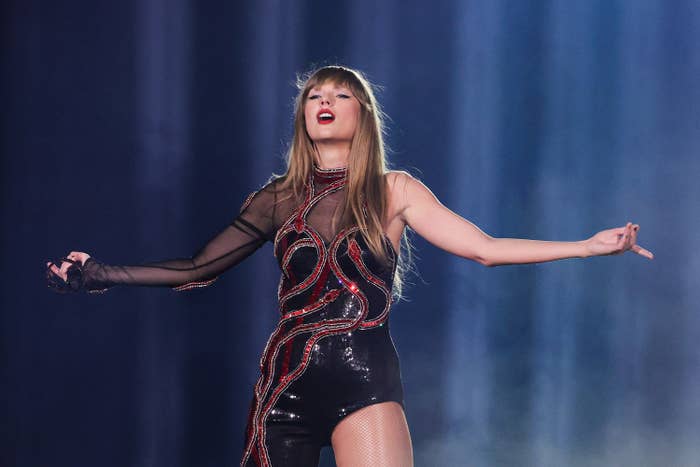 Taylor Swift onstage with her arms outstretched, head tilted back