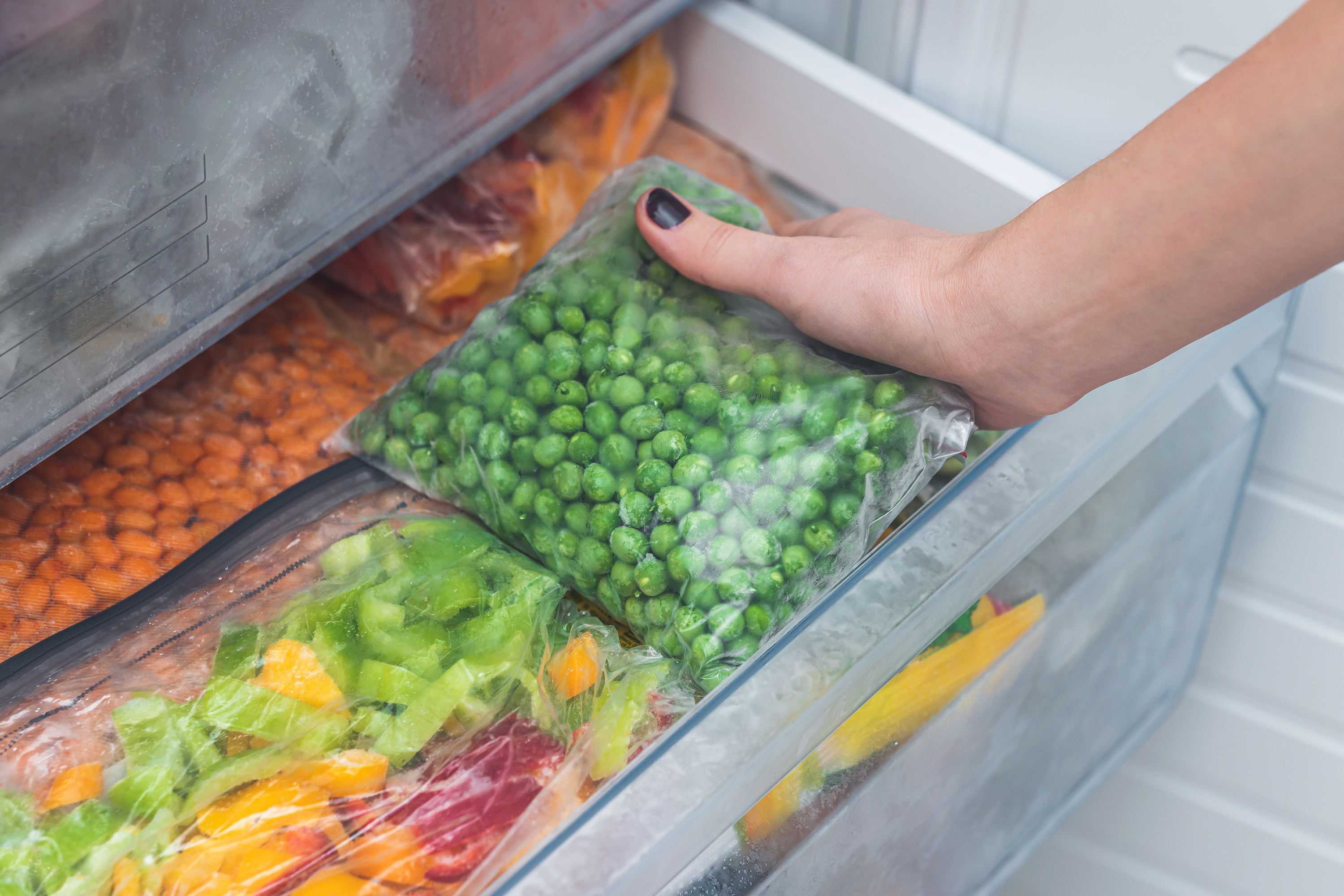 girl takes frozen vegetables from the freezer
