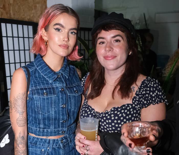 Bella with long hair and wearing a cap with tattoo artist Sophie Floyd