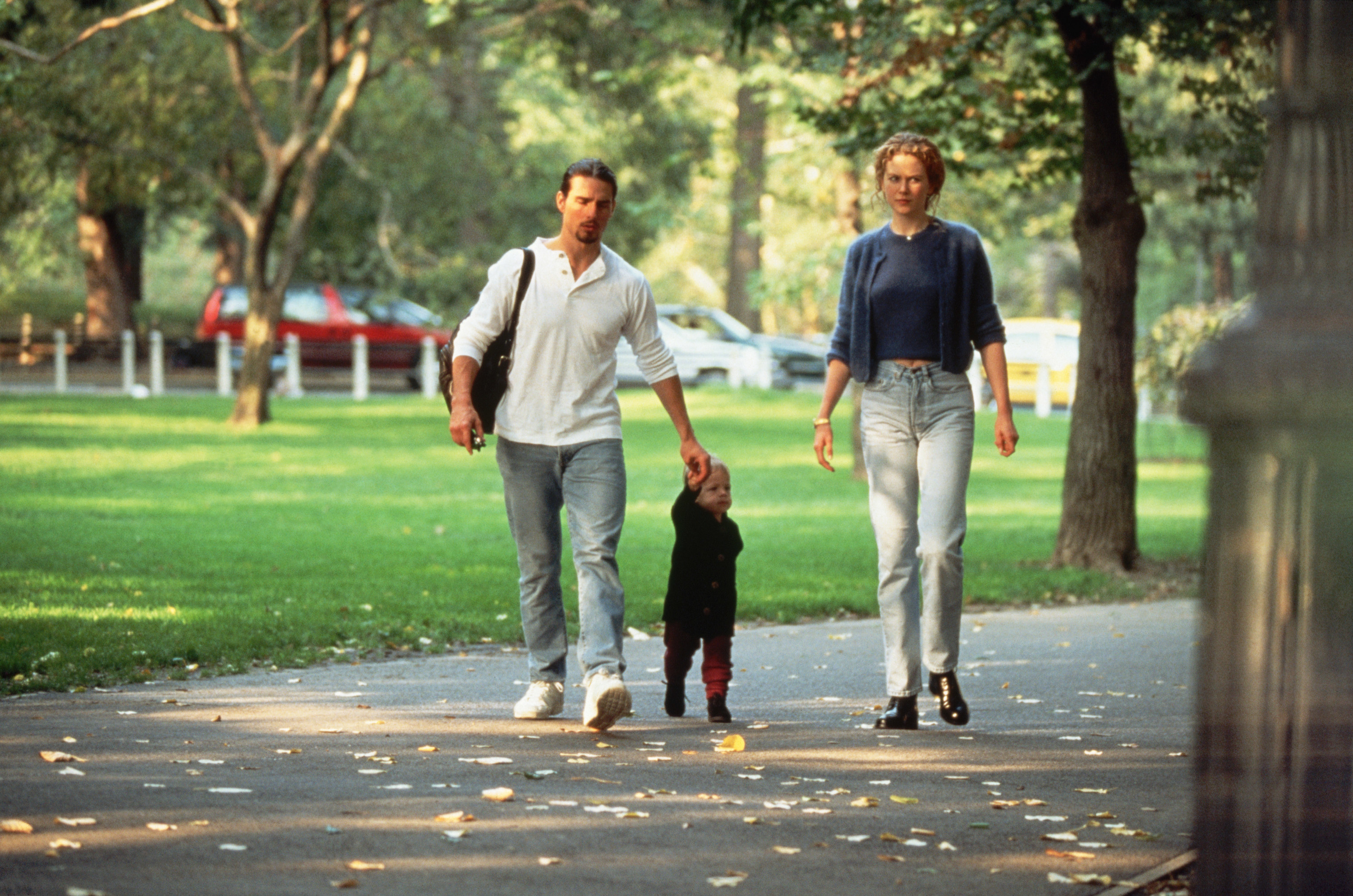 Tom&#x27;s holding Bella&#x27;s hand as they walk on a path near grass