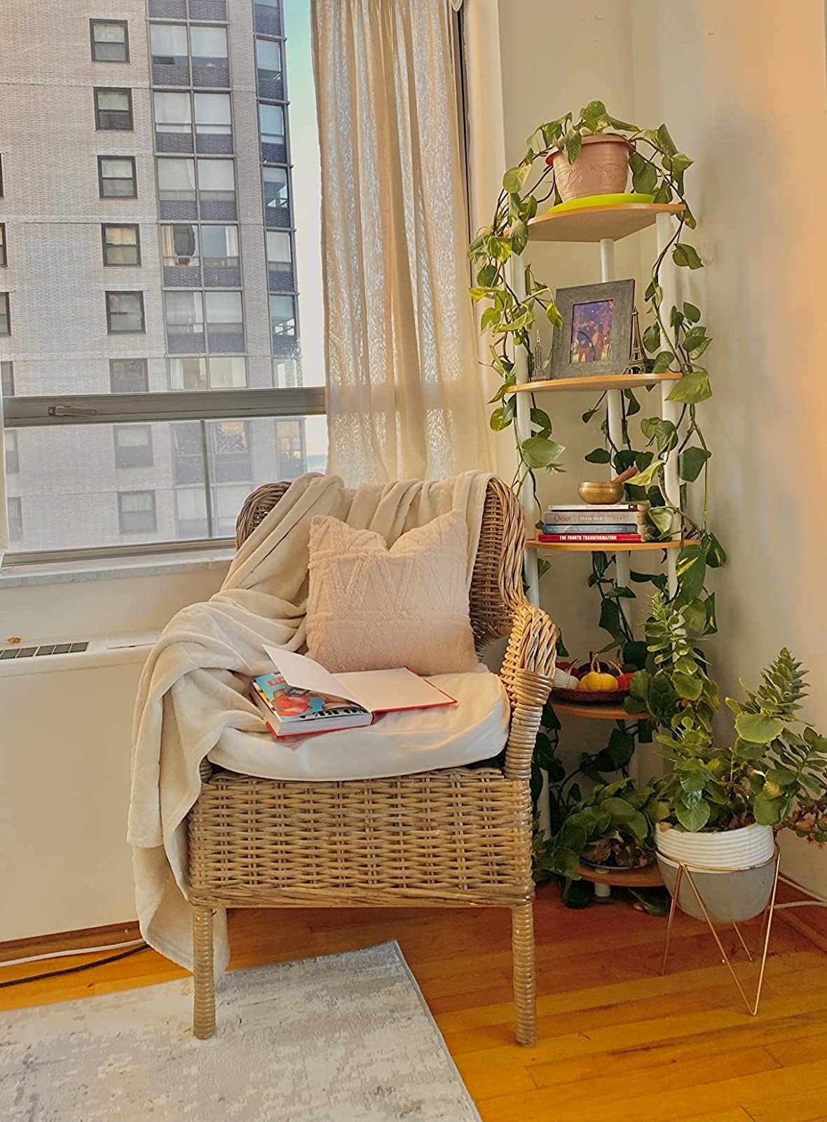 a reviewer photo of the white and brown shelf with a climbing plant in a corner behind a well-styled chair