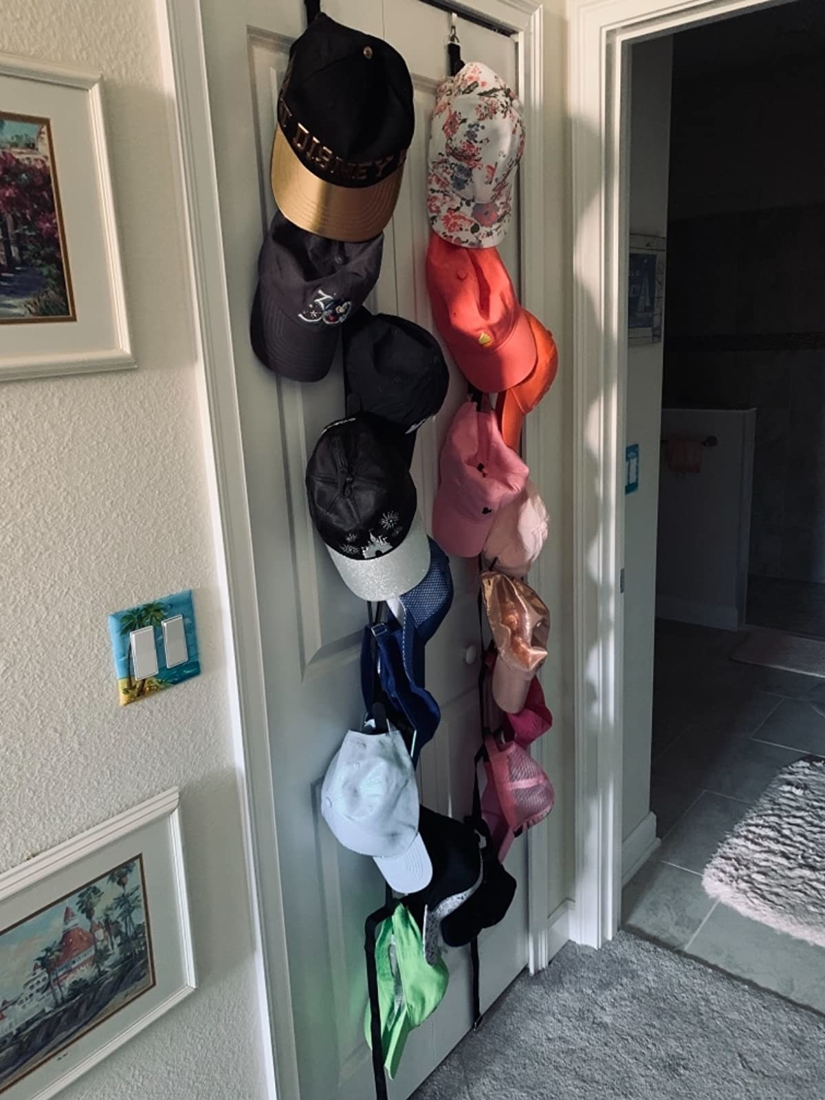 a reviewer photo of a rainbow of hats hanging on the over the door rack