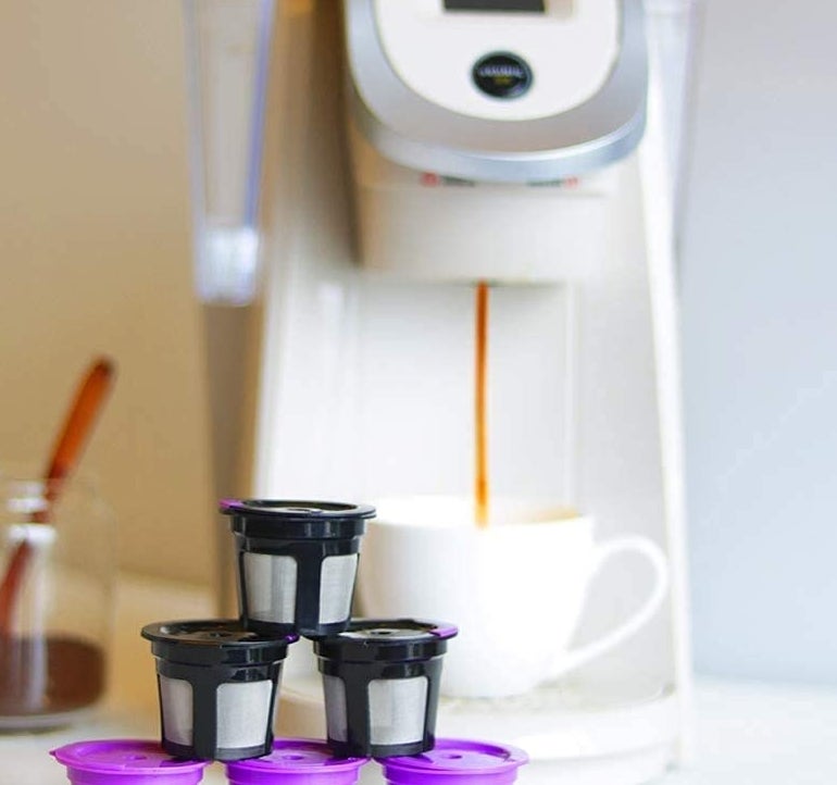 the pods lined up pyramid style next to a keurig pouring coffee into a cup