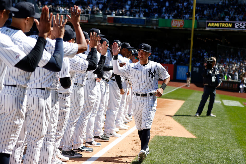 a yankees baseball player high fiving his teammates out on the pitch