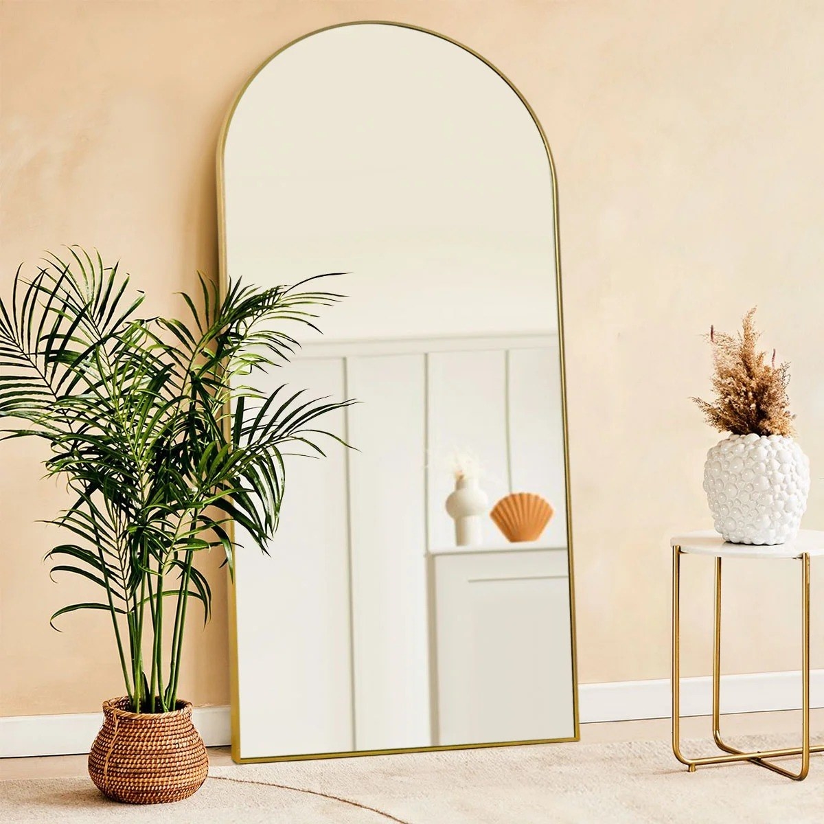 The large arched mirror with a gold frame leaning against a wall