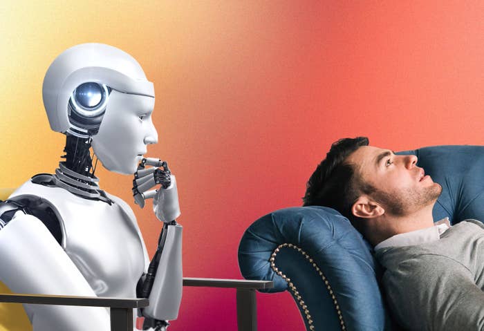 An android robot holds its hand up to its chin while listening to a man who is laying on a couch talk