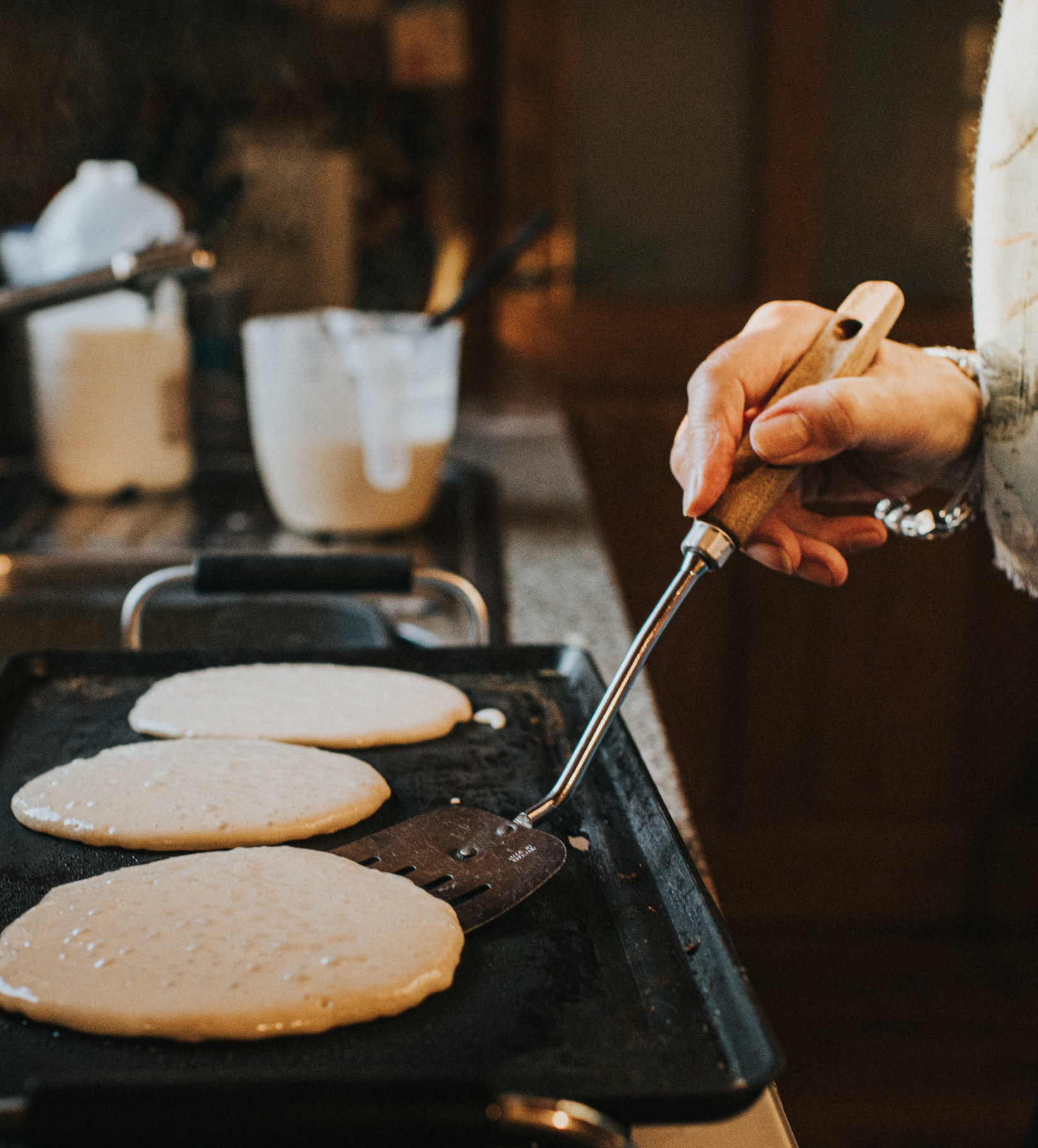 Woman flipping pancakes on a grill.