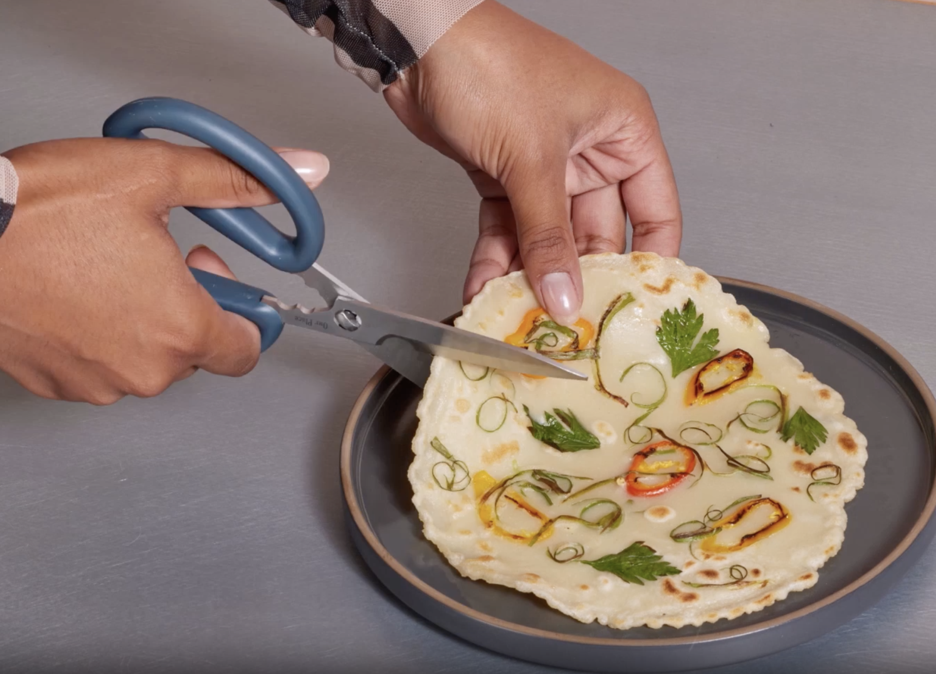 A person cutting a veggie pancake with the scissors