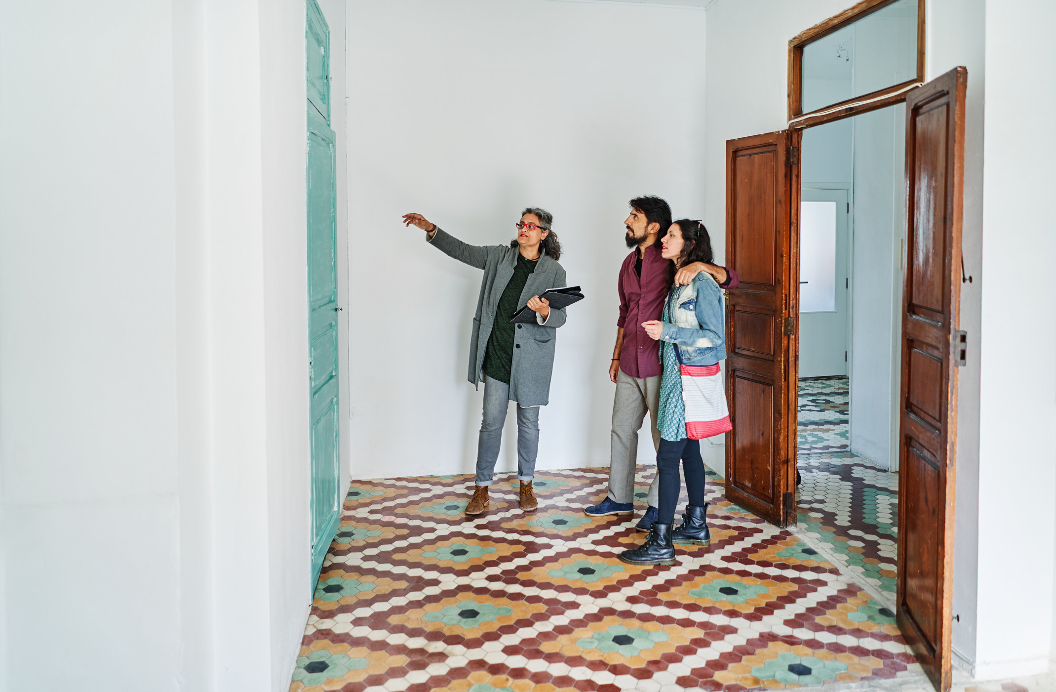 A real estate agent shows a young couple the interior of a home