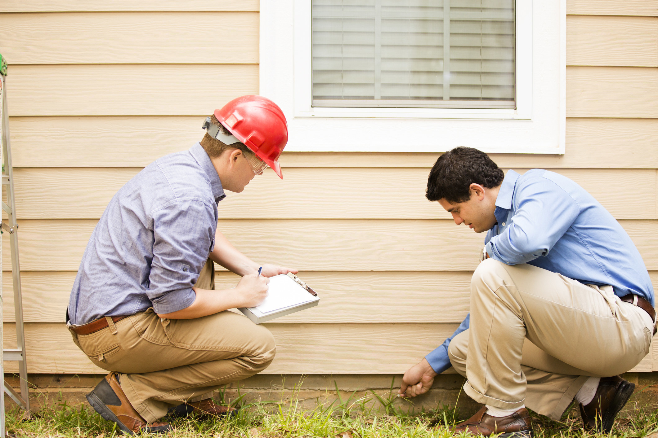 Two home inspectors evaluate the exterior of a home