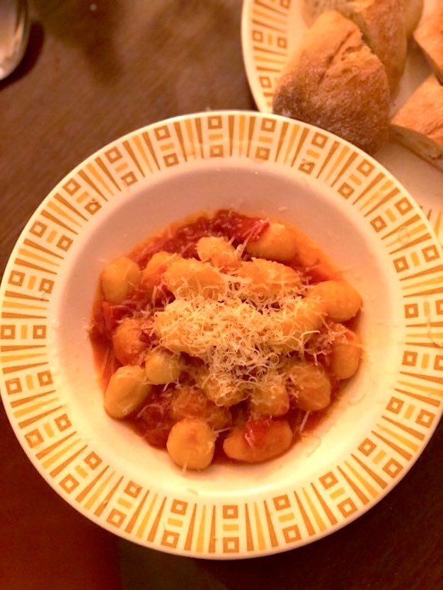 plate of gnocchi piled into a shallow bowl, served with bread