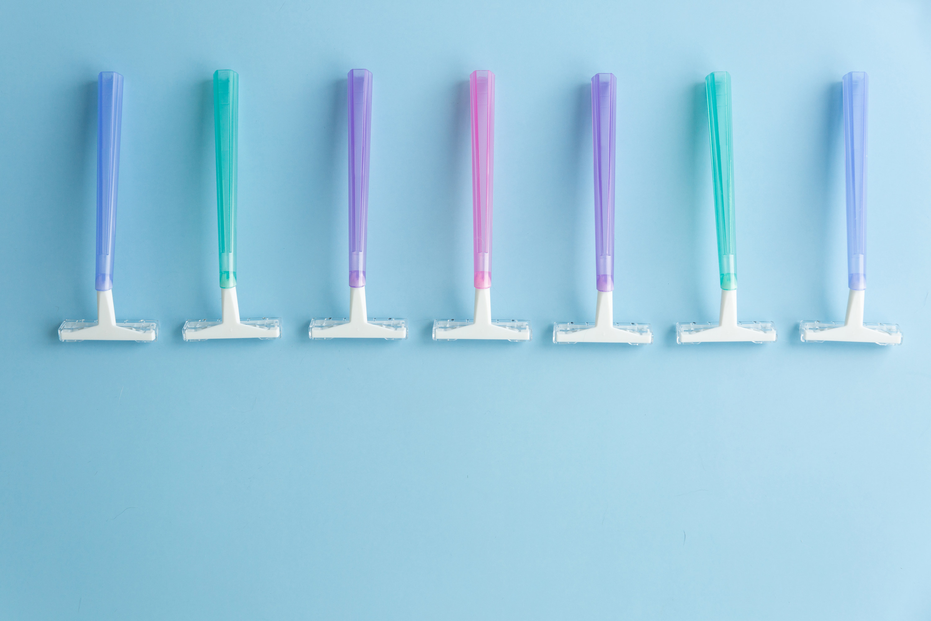 Set of multi-colored disposable razors on a blue background