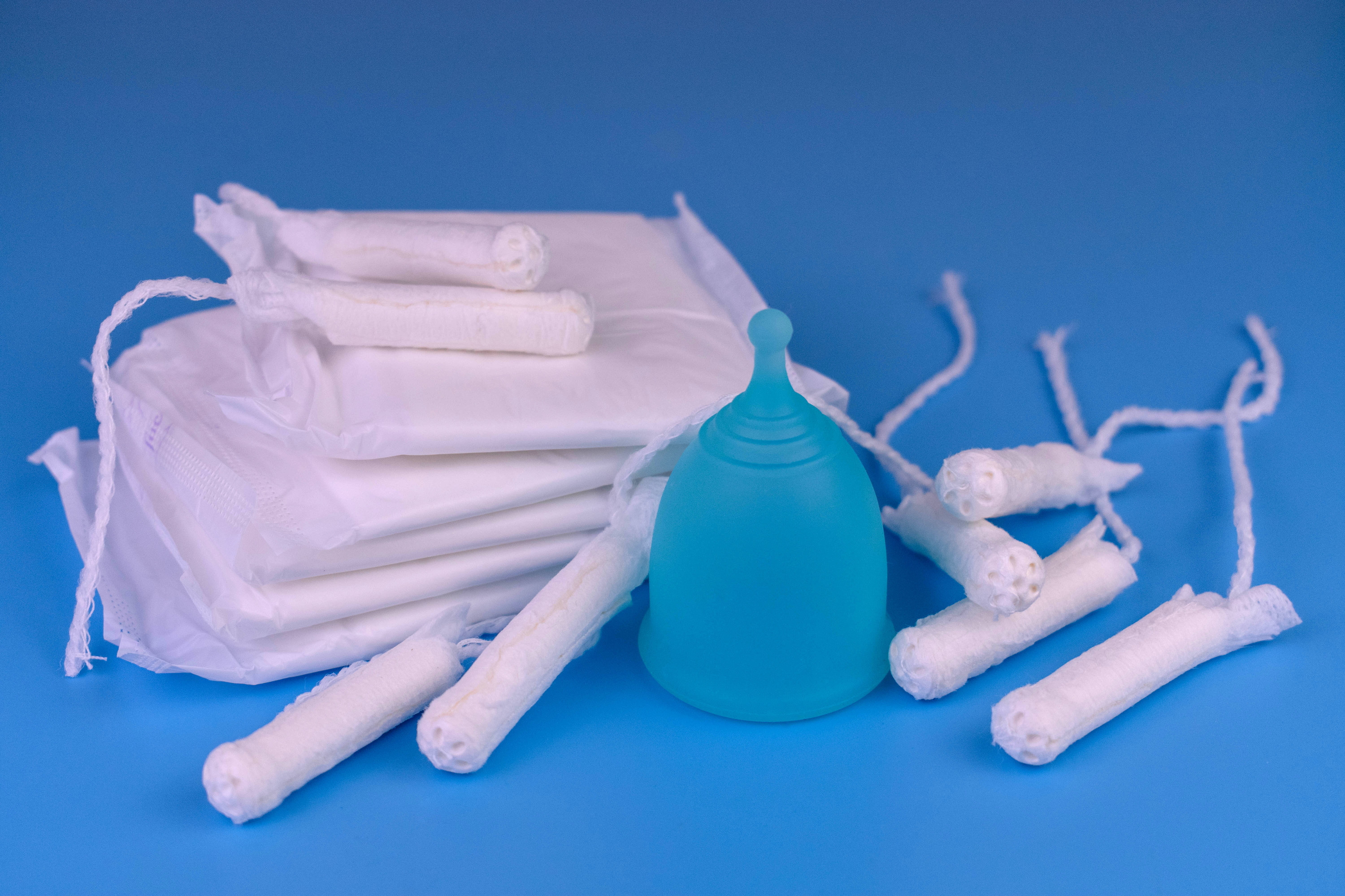 Varieties of personal hygiene products for women: tampons, pads, menstrual cup on a blue background