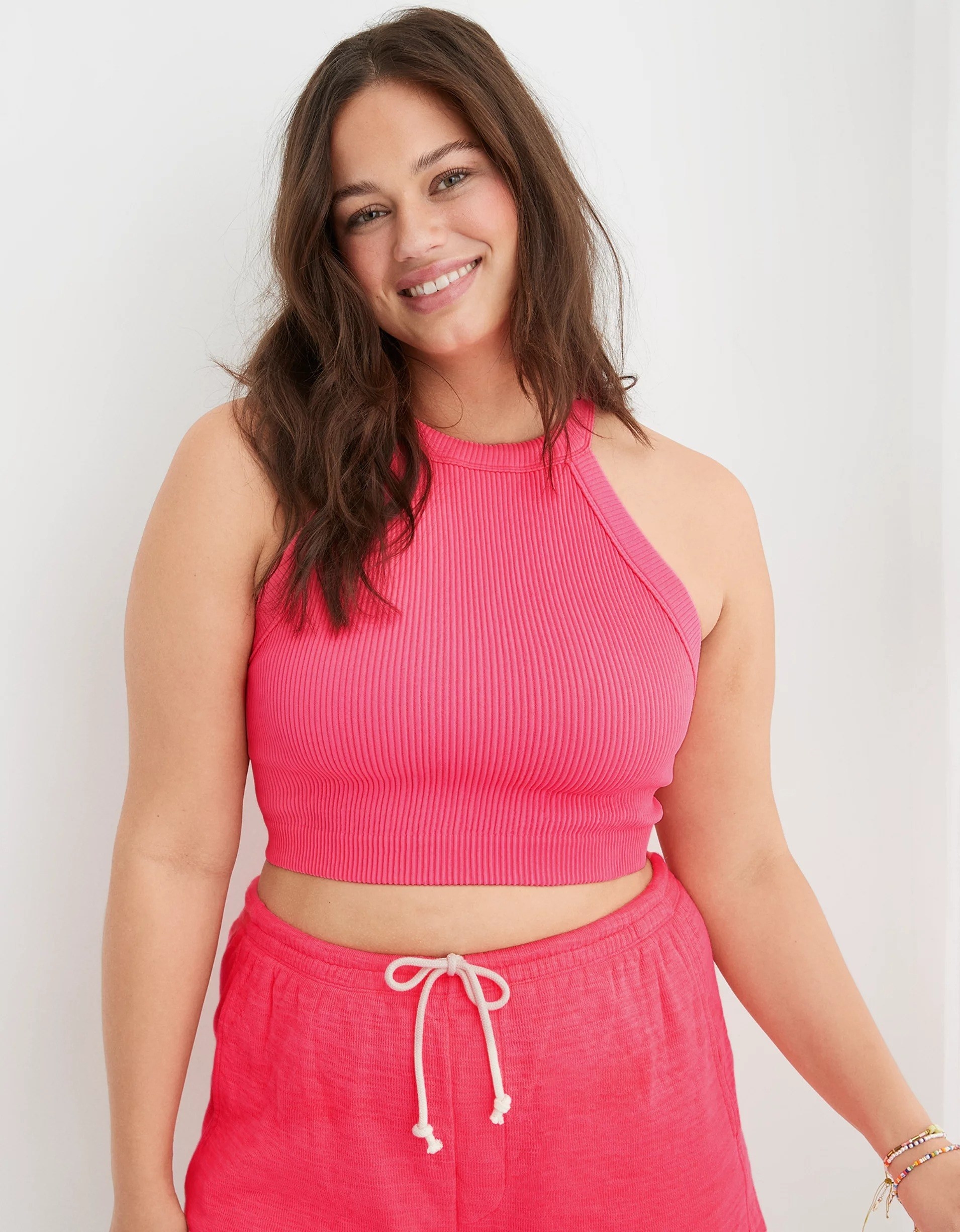 A model wearing the bralette in pink with matching bottoms