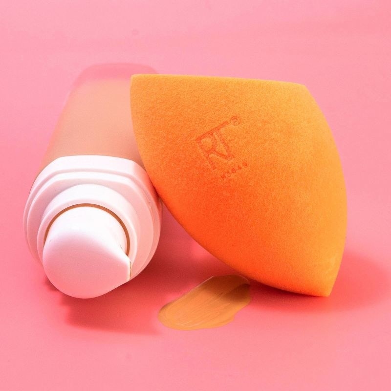 A bottle of liquid makeup, a swatch of product, and an orange makeup sponge
