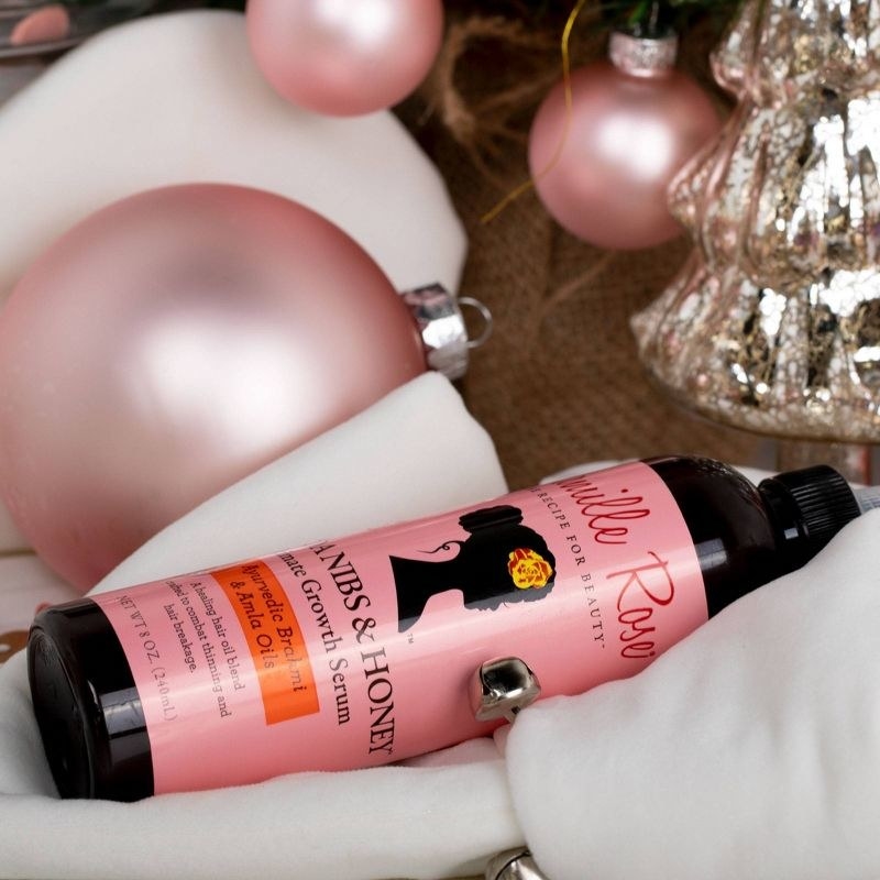 A bottle of hair growth serum with pink ornaments