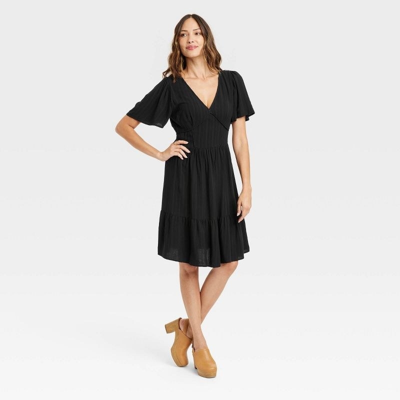 A model in the dress in black with clogs