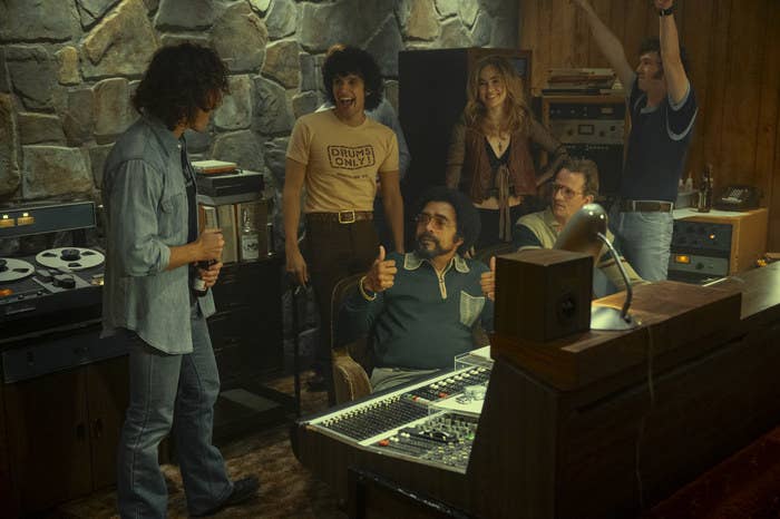 Still from Daisy Jones & the Six of bandmates cheering in the recording studio.