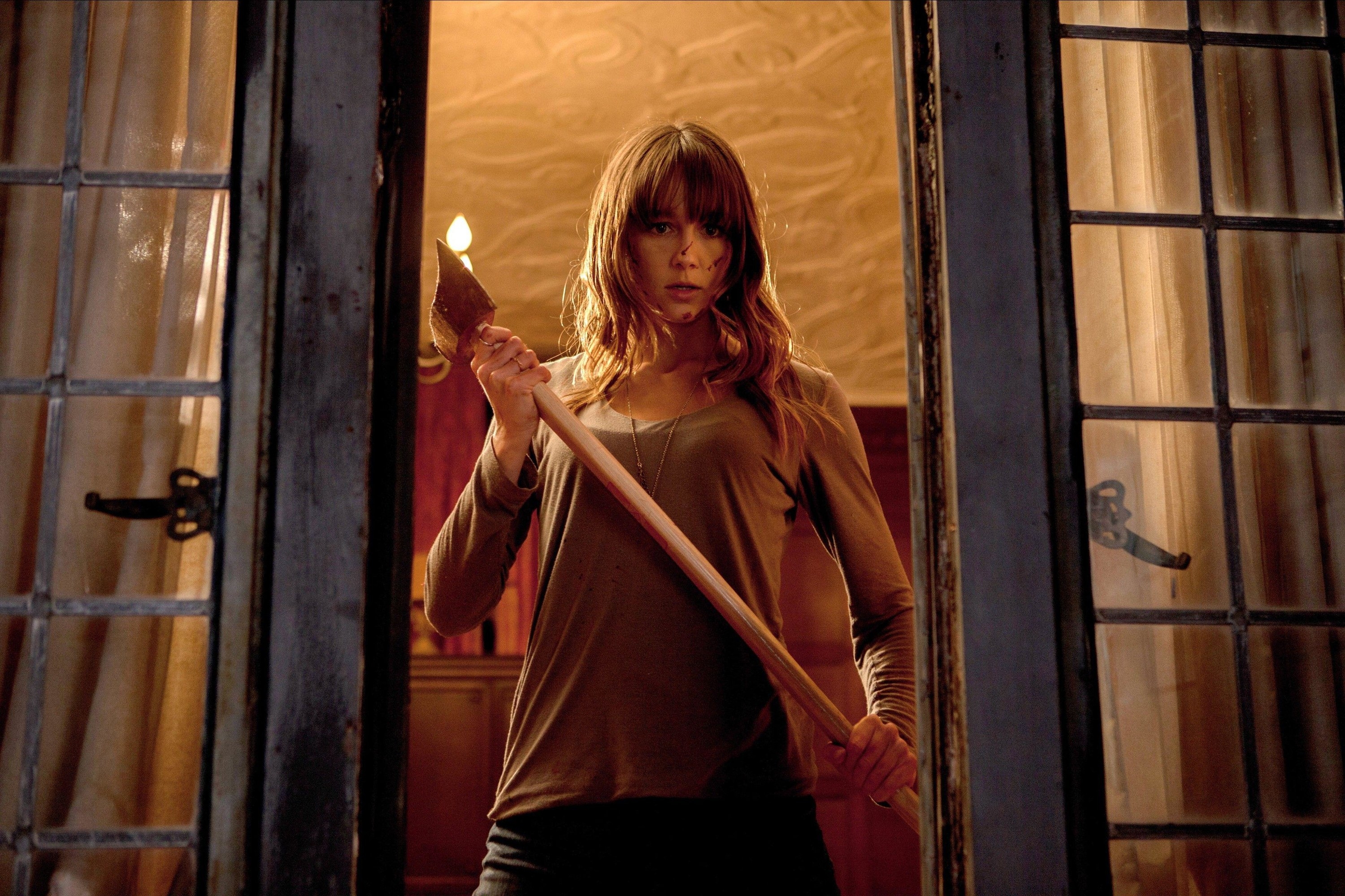 Sharni Vinson stands in an open window holding an axe in an intimidating fashion