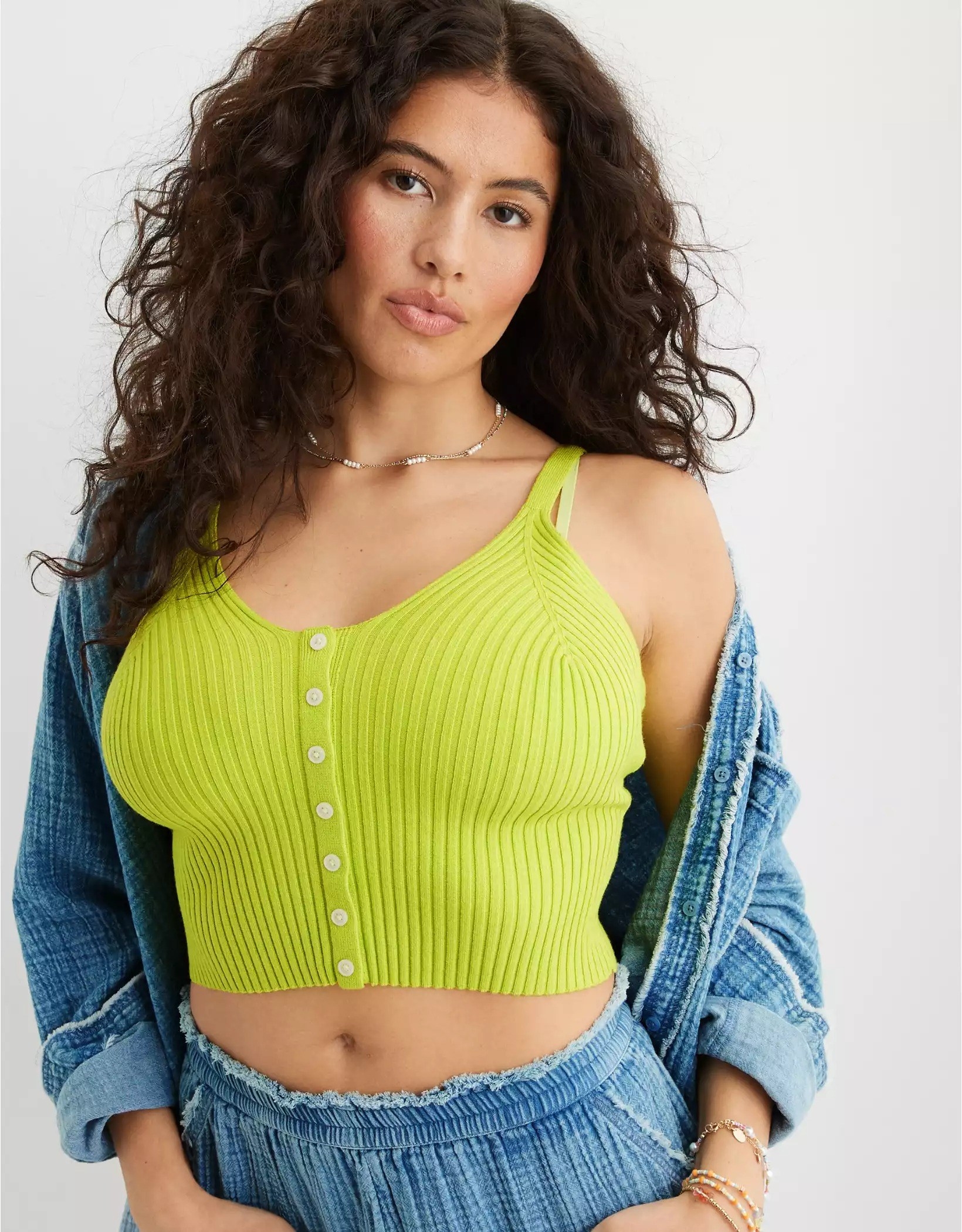 A model wearing the sweater tank in green with shorts and a button-down as cover-up