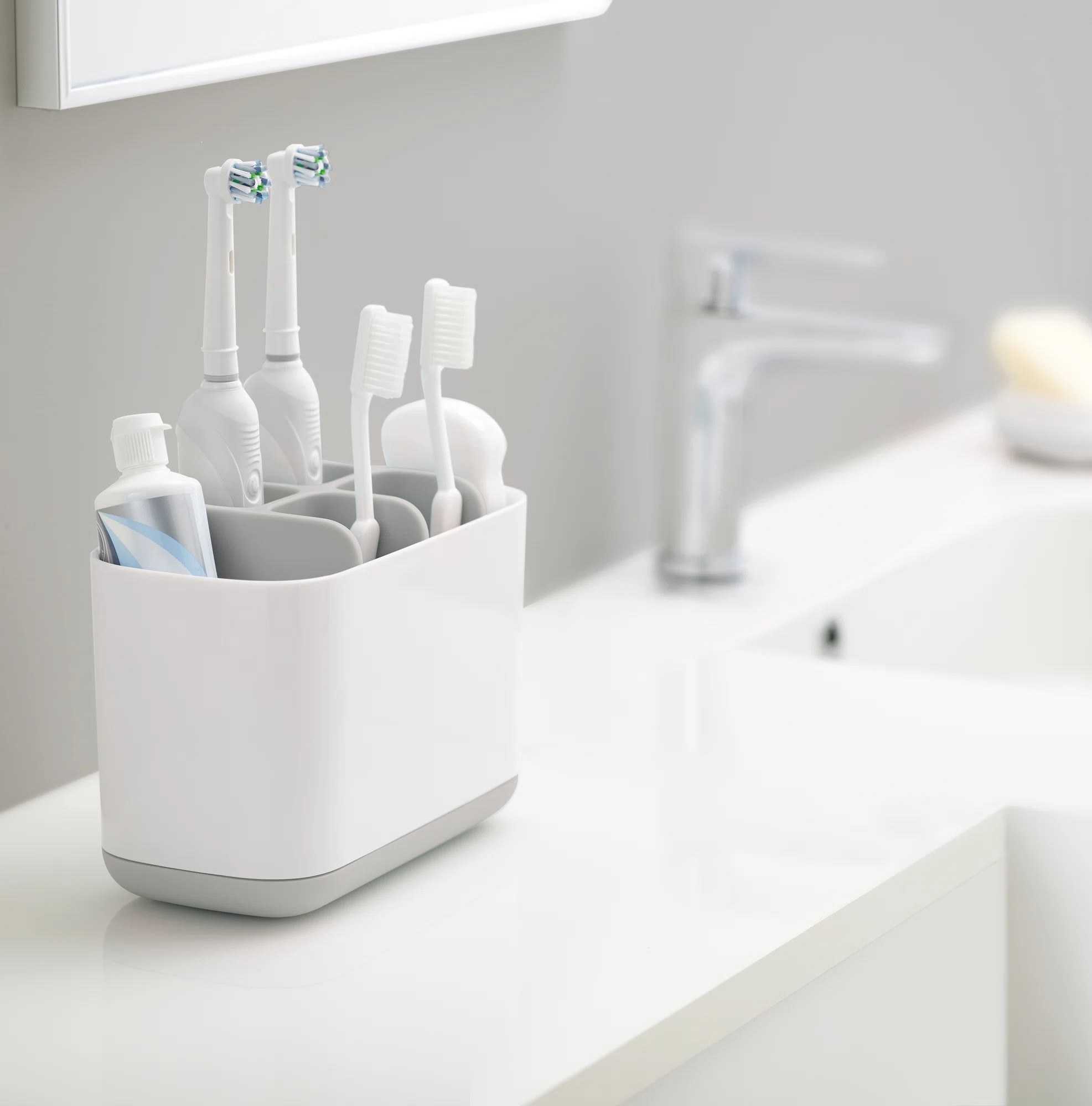 a white and gray toothbrush holder holding four toothbrushes and toothpaste