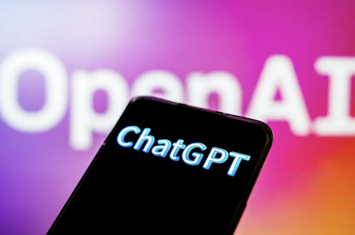 a phone screen that reads &quot;chat gpt&quot; against a blurry pink/purple background that reads &quot;open ai&quot;