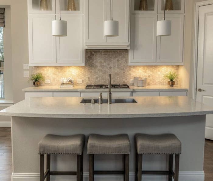 A kitchen with a counter top illuminated by under cabinet lights