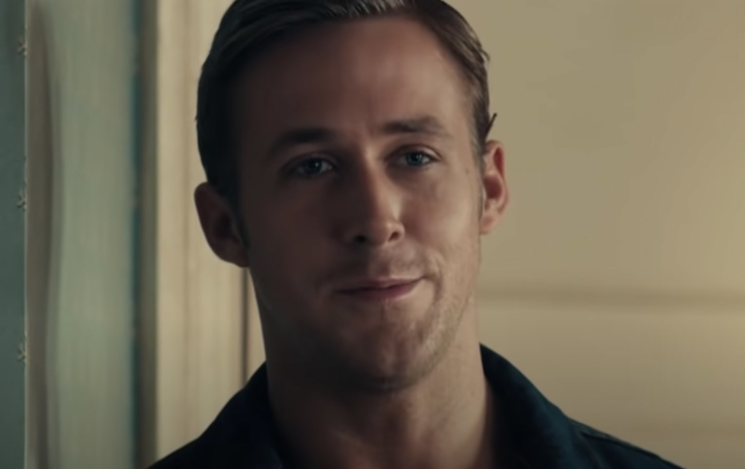 Ryan Gosling smiles with his mouth closed as the Driver in Drive