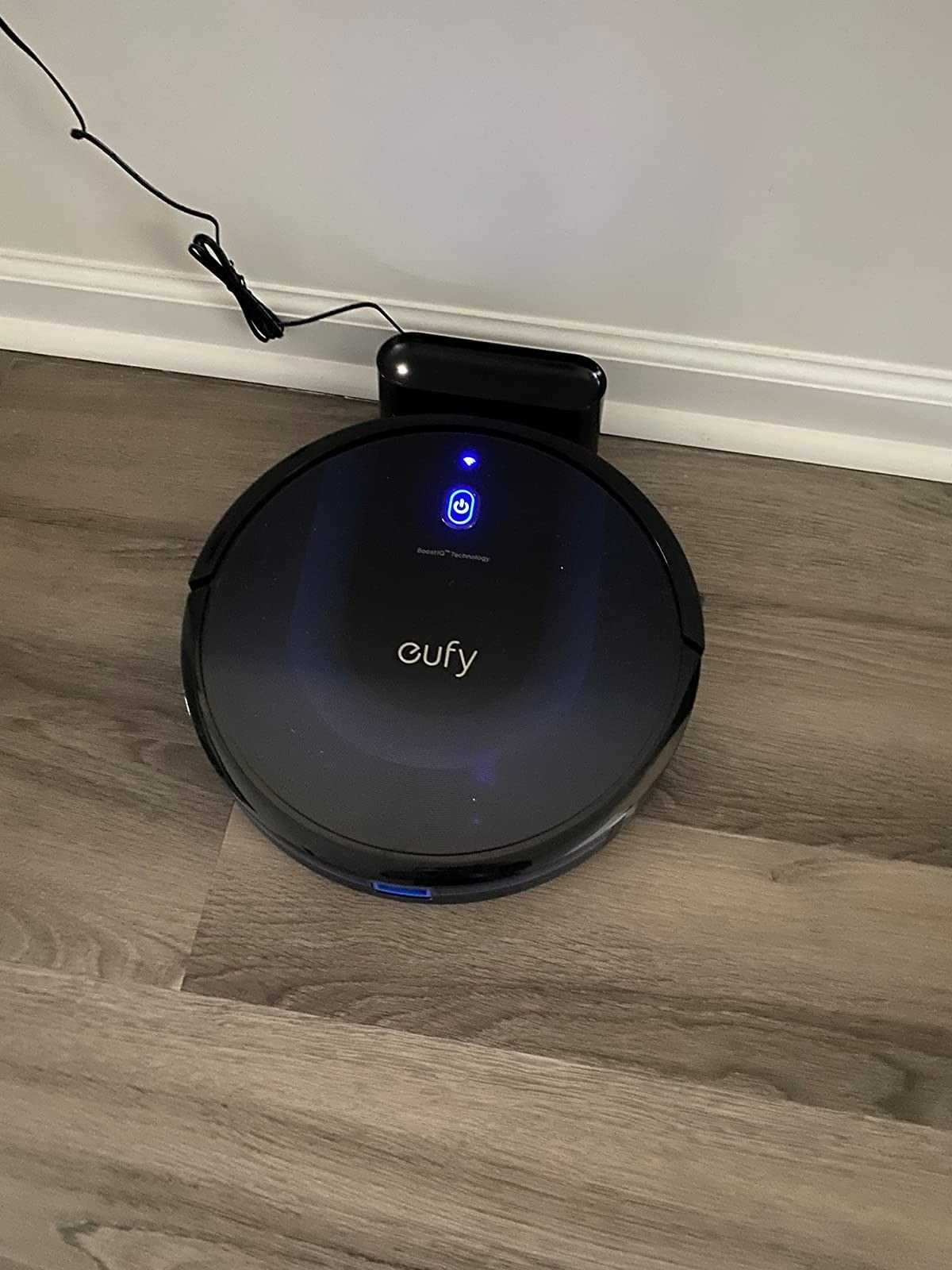 black robot vacuum on charging doc plugged into wall outlet