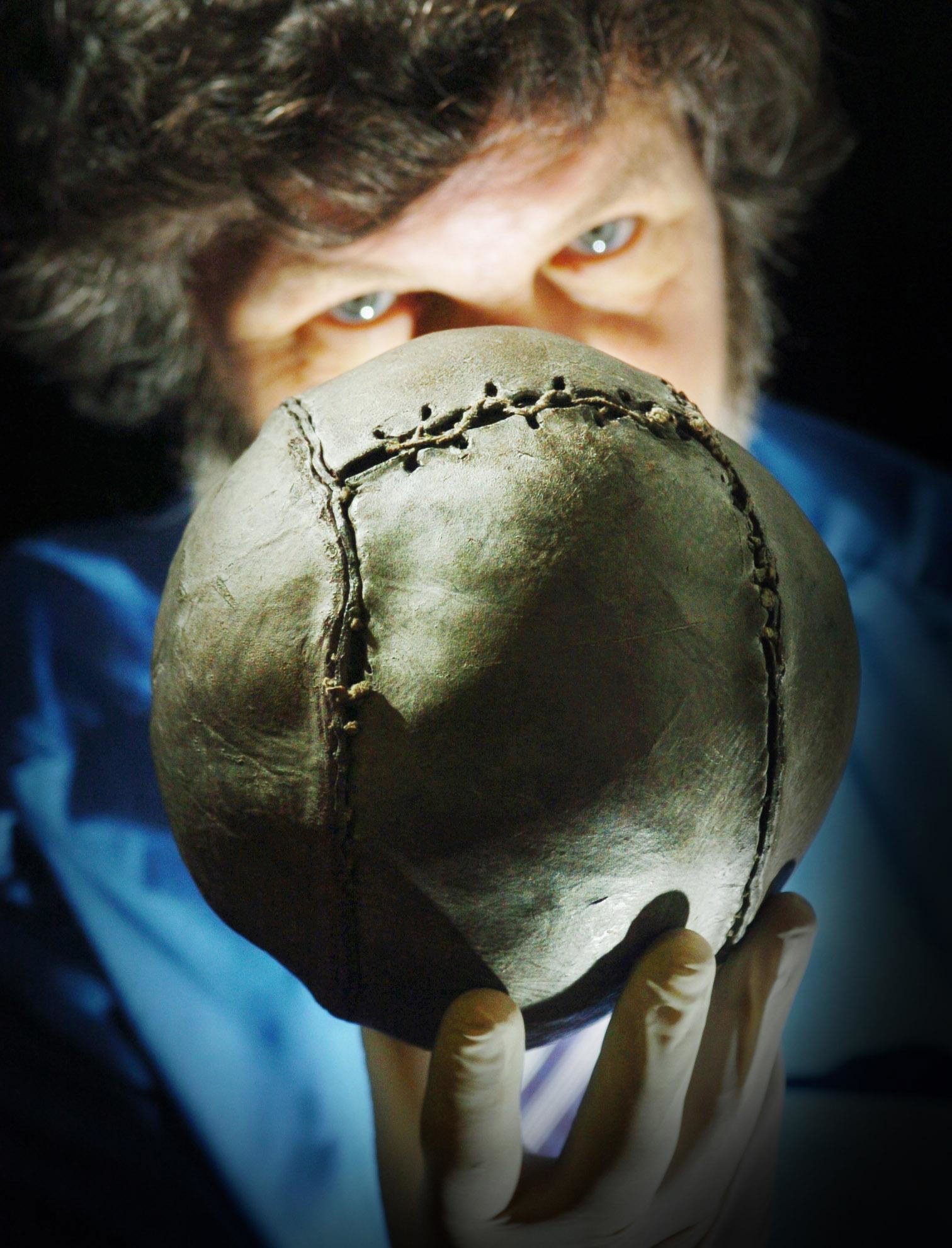 A man holding an old soccer ball