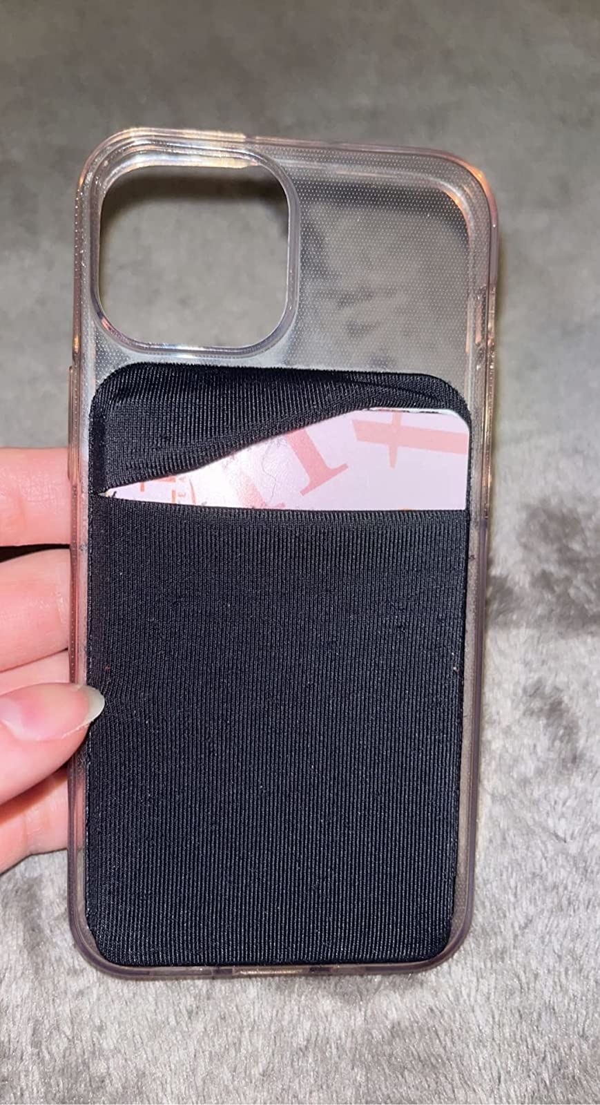 reviewer&#x27;s phone case with the black wallet attached and credit cards in the pocket with top cover slipped over except for one corner