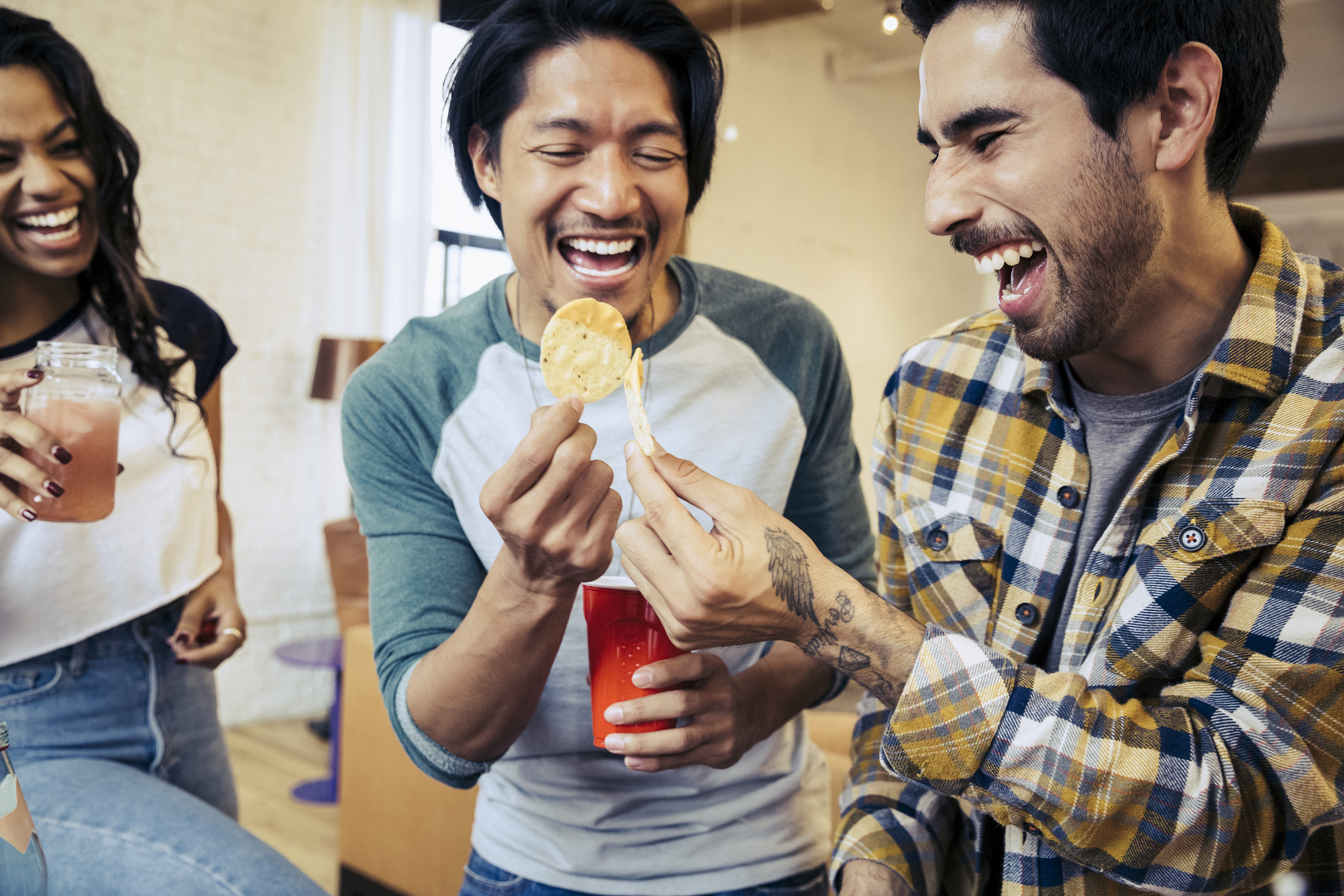 Two men laugh while snacking together