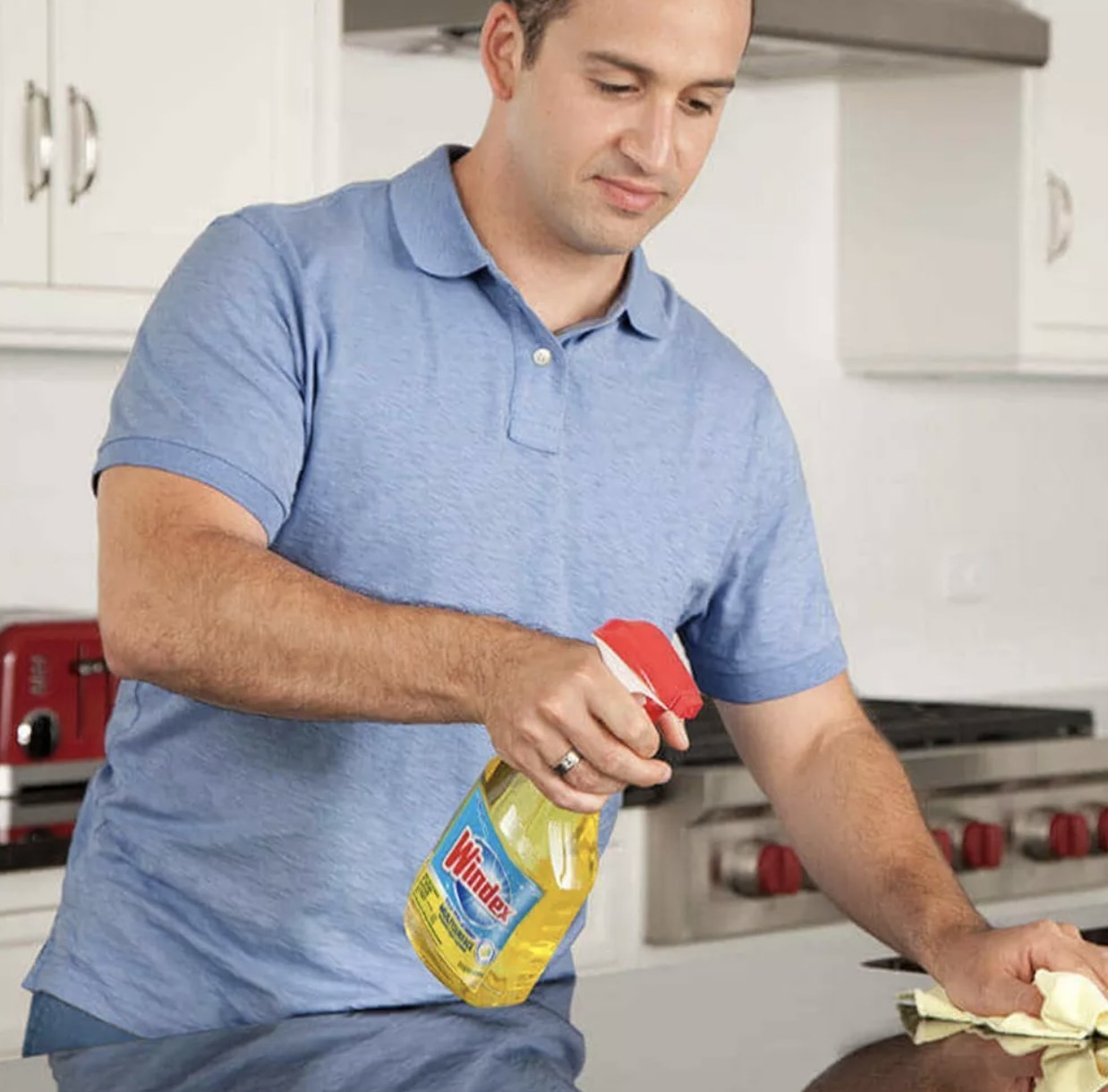A person in a blue shirt using a yellow surface spray