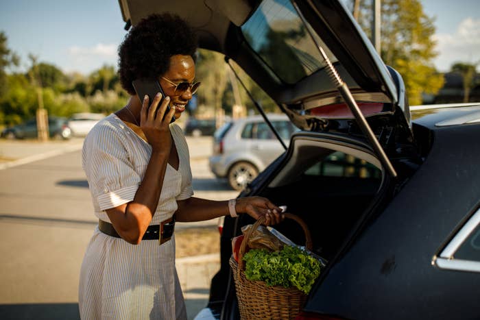 someone loading groceries into car trunk