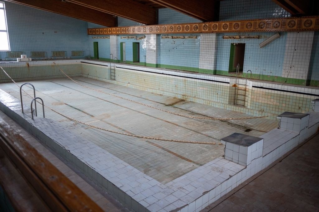 a bleak room and a completely drained pool, covered in grime