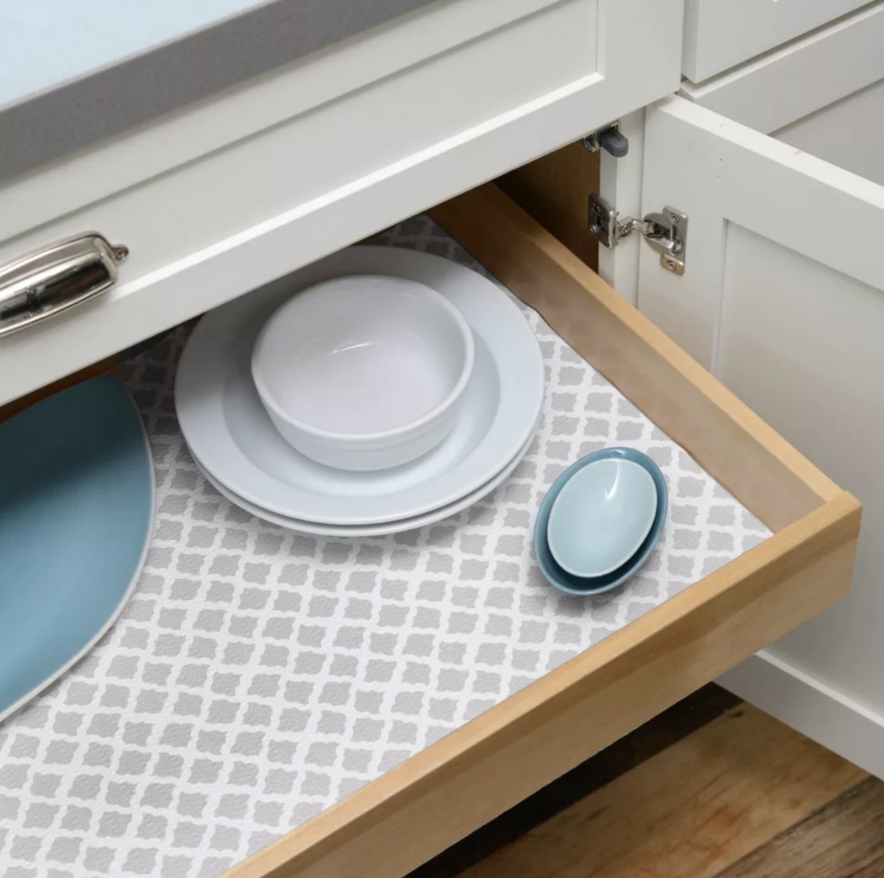 A drawer lines with grey and white paper with dishes in it