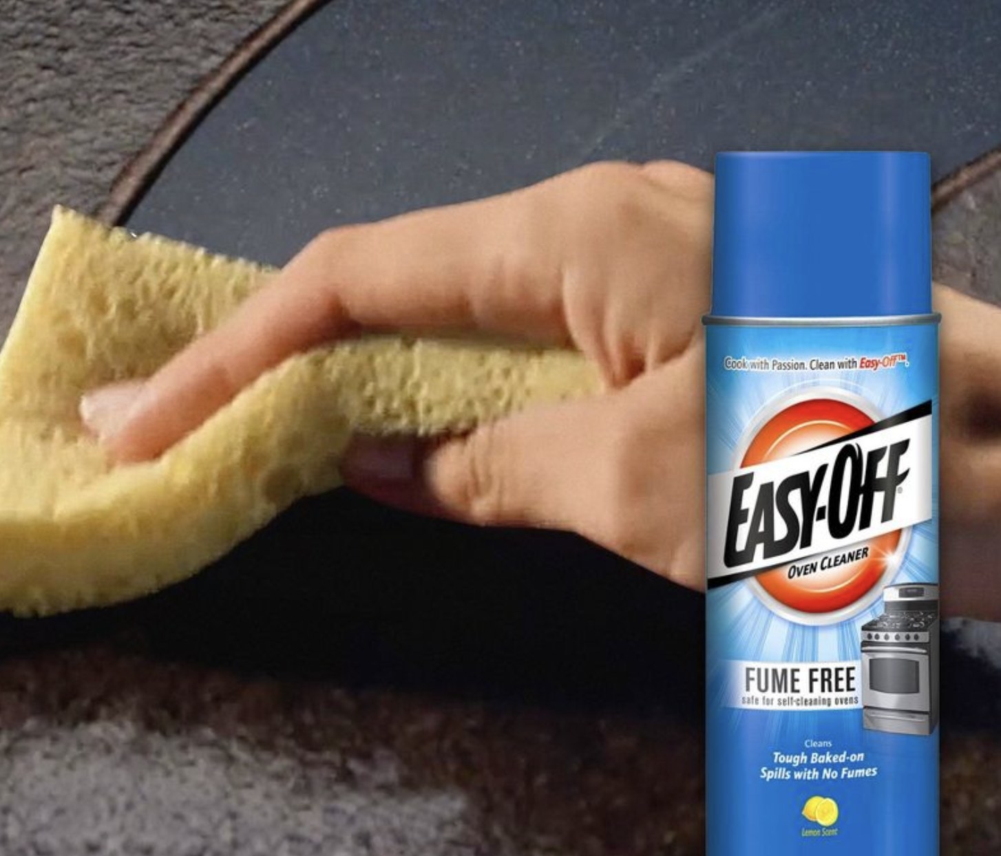 A hand using a yellow sponge behind a can of oven cleaner
