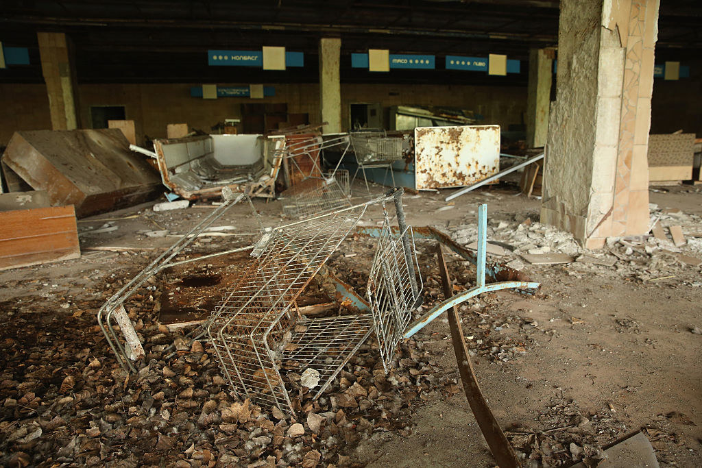 shopping cart tipped over in dust outside.a crumbling grocery store