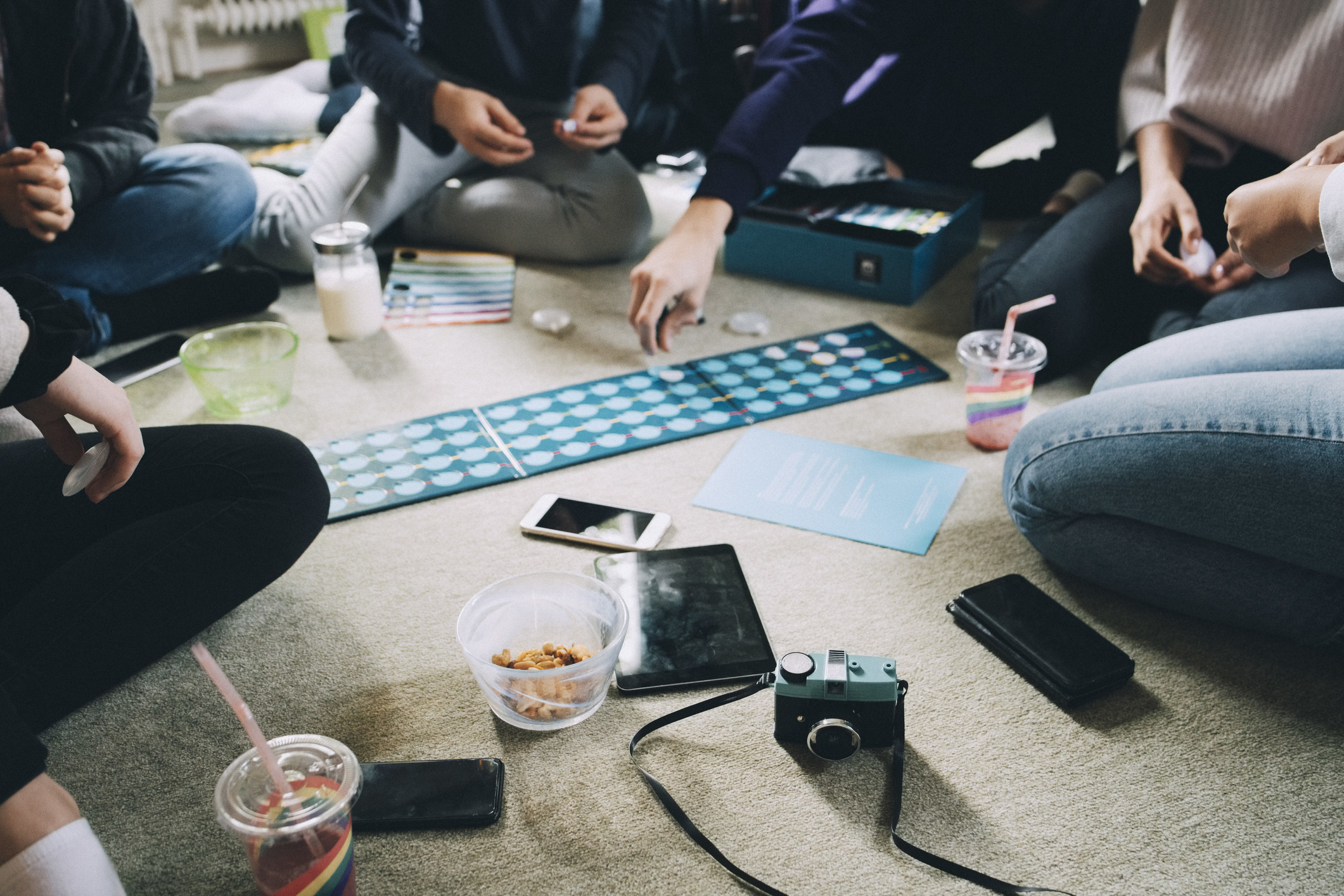 A group of people playing a board game on the floor