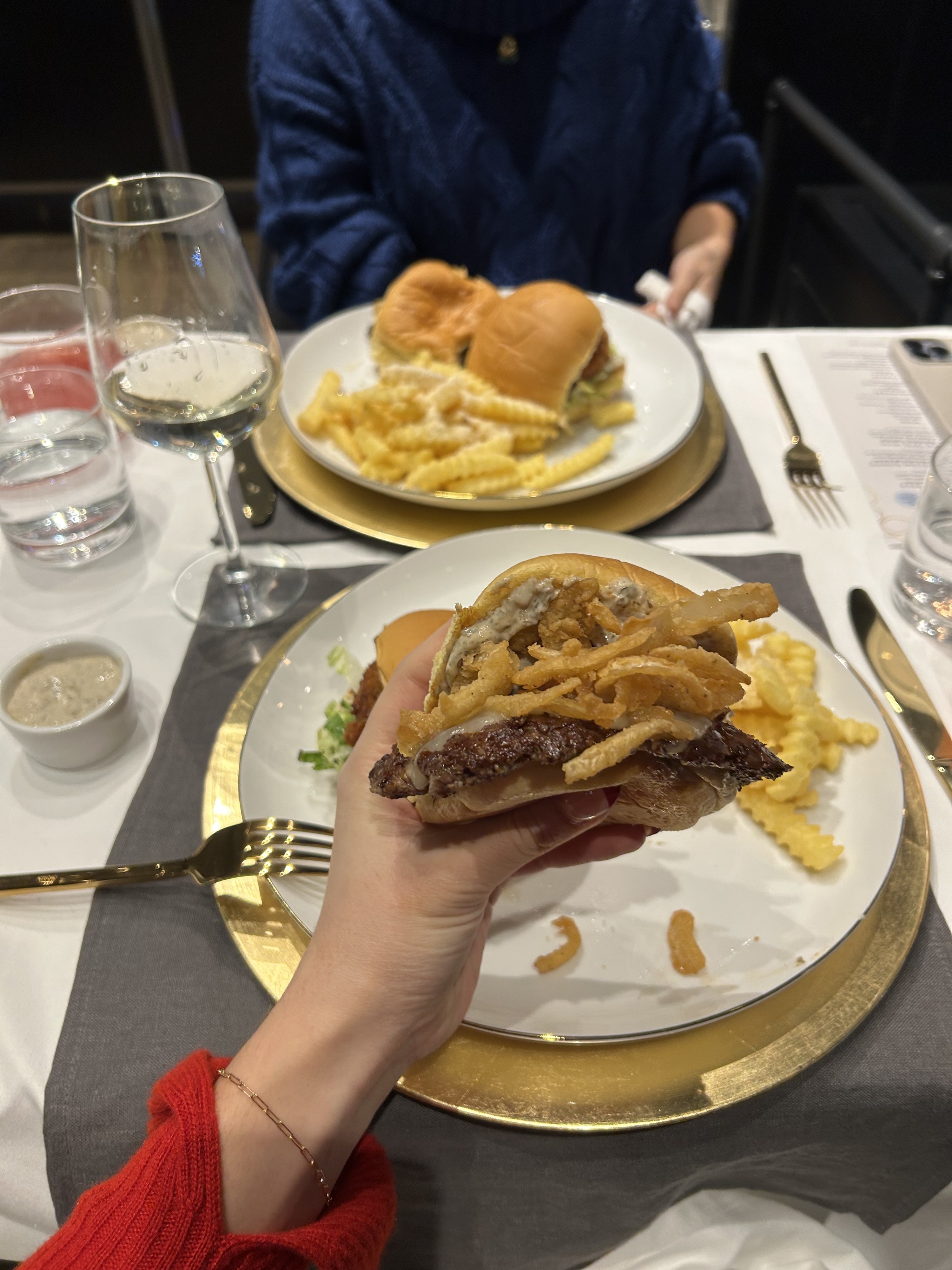 A hand holding the White Truffle Burger over a plate