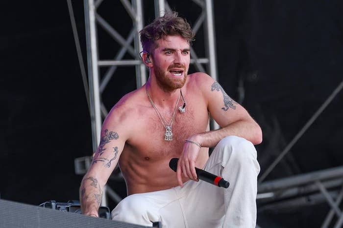 Andrew Taggart, who shirtless, squats while performing onstage