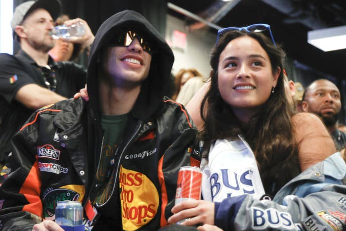 Pete and Chase sitting next to each other and holding cans of drinks as they watch an event