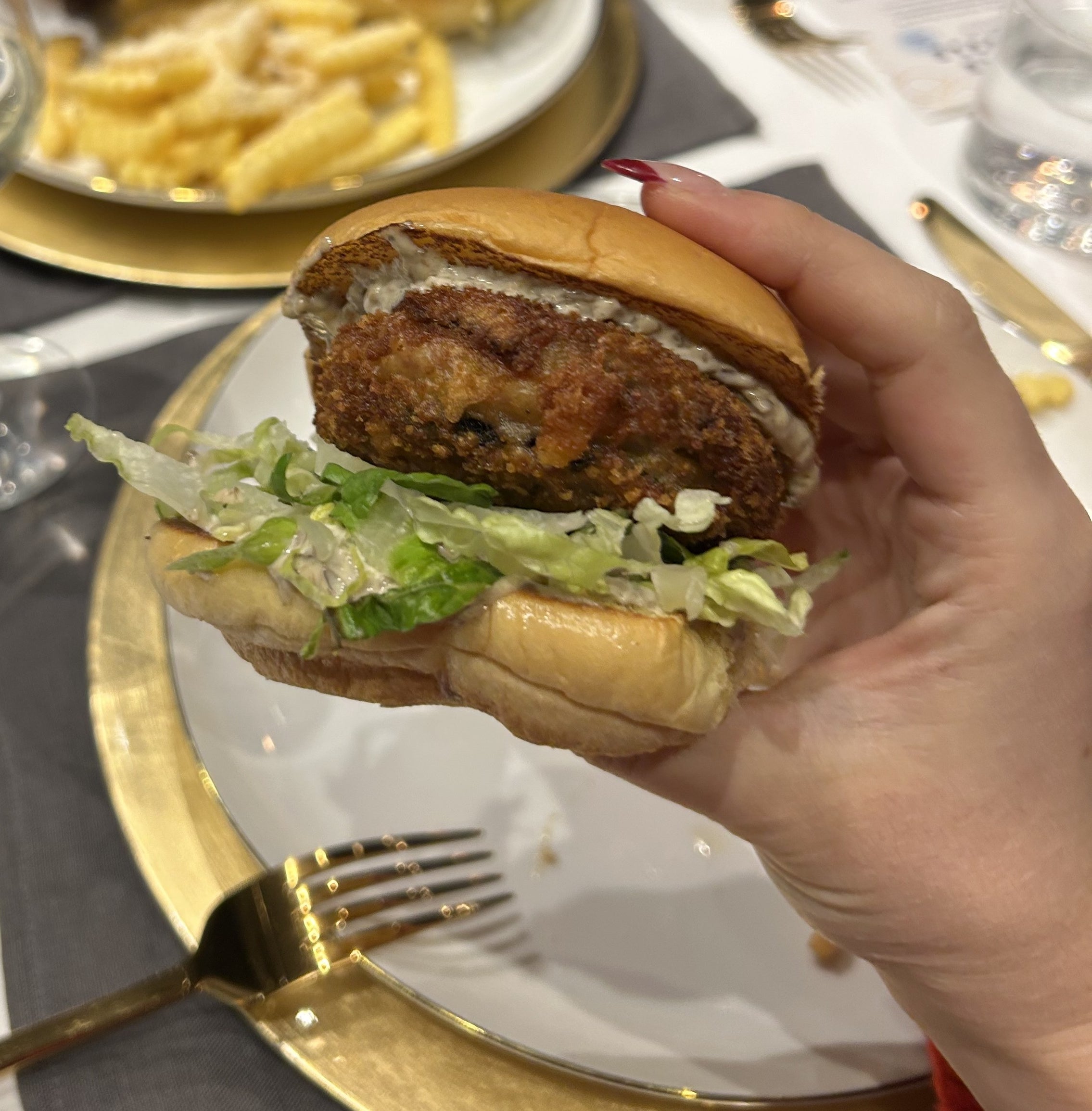 A hand holding the White Truffle &#x27;Shroom Burger over a plate