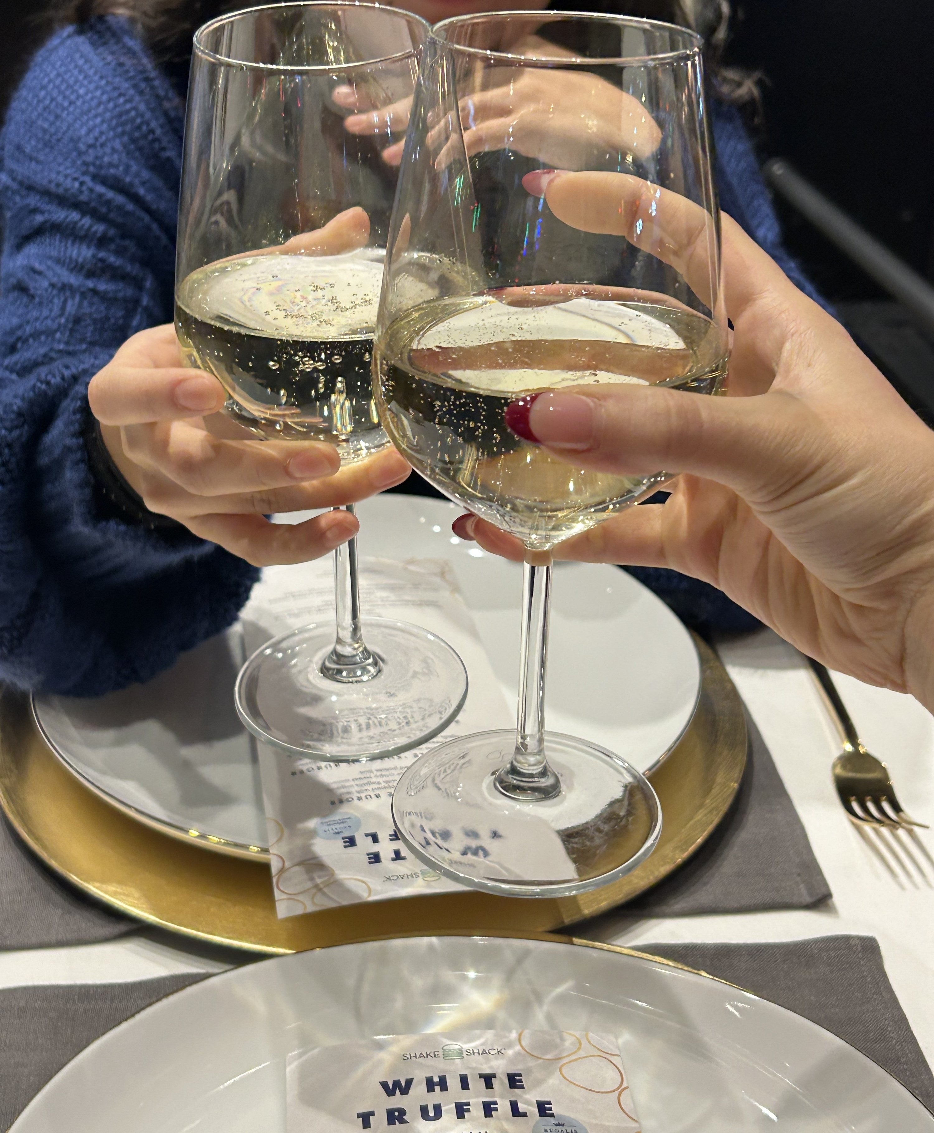 Two people touching wine glasses at a table