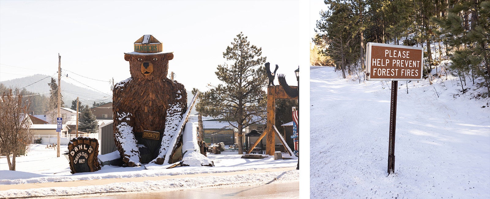 A towering sculpture of Smokey The Bear sitting in the snow and created from scraps of wood, wearing a wooden hat that says “Rangers” in Hill City, South Dakota next to a sign that says “Please help prevent forest fires”