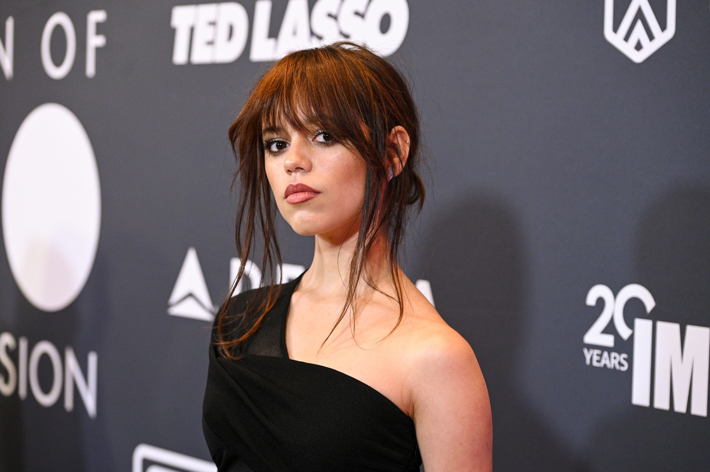 Close-up of Jenna with her hair up and wearing a one-shoulder outfit on the red carpet